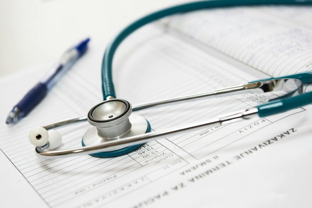 A stethoscope and a blue pen resting on top of a medical chart with patient information and handwritten notes.