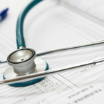 A stethoscope rests on an open medical chart with a pen nearby, symbolizing healthcare, diagnosis, and medical documentation.