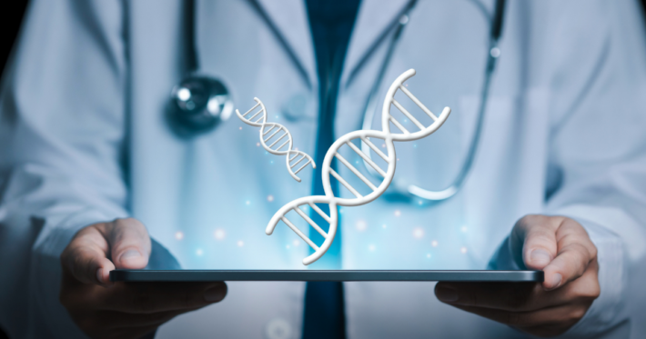 A doctor in a white coat with a stethoscope holds a digital tablet displaying floating DNA double helix graphics, representing genetic research or medical technology.